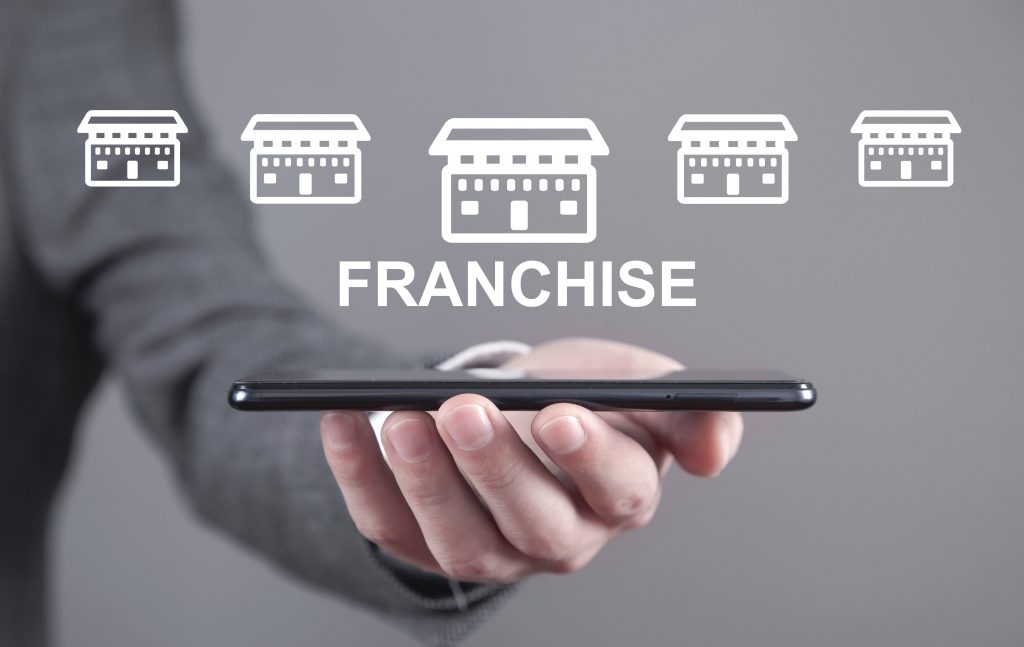 Man holding smartphone with a Franchise icons.